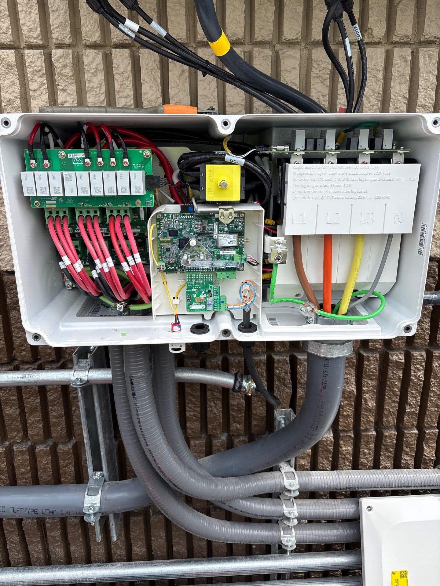 Open solar combiner box with DC wiring, optimizers, and three-phase AC terminations