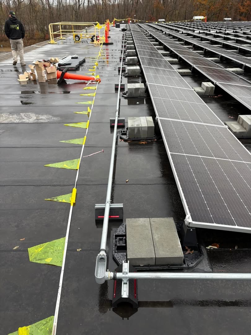 Solar racking and conduit installation on a wet commercial roof with safety flagging