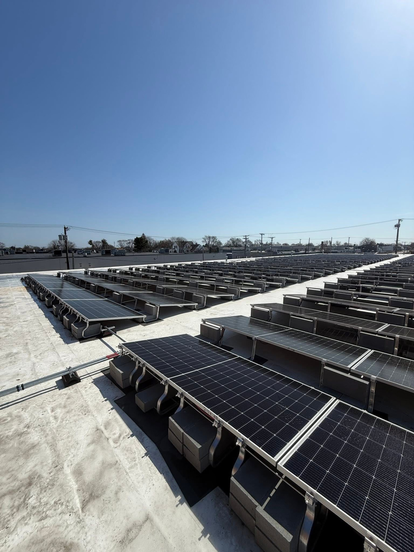 Rows of solar panels installed on a white flat commercial roof on a clear day