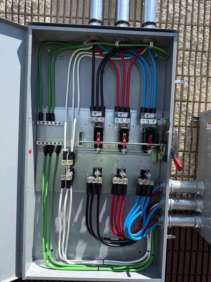 Open electrical disconnect enclosure with color-coded three-phase feeders neatly terminated